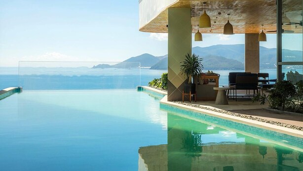 A modern infinity pool with a clear view of the ocean and mountains in the background. - Panorama Nha Trang Hotel & Apartments (Nha Trang)