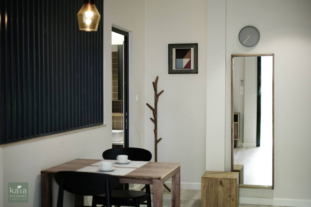Un comedor con una mesa de madera, sillas, una planta pequeña y un reloj en la pared.