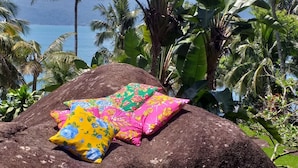 A rock with colorful pillows in a tropical setting. - GuestHouse Elephant Ilhabela (Urubu)