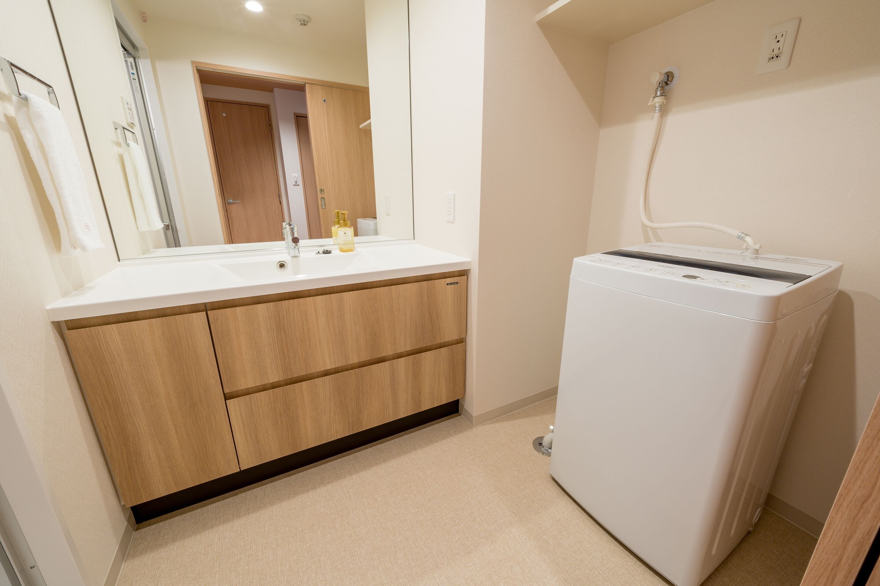 A bathroom with a white sink, wooden cabinets, a mirror, and a white washing machine.