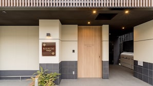 A hotel entrance with a reception desk, a wooden door labeled "RESI STAY Nishijin," and a grill area in the background. - RESI STAY Nishijin  (Kyoto)