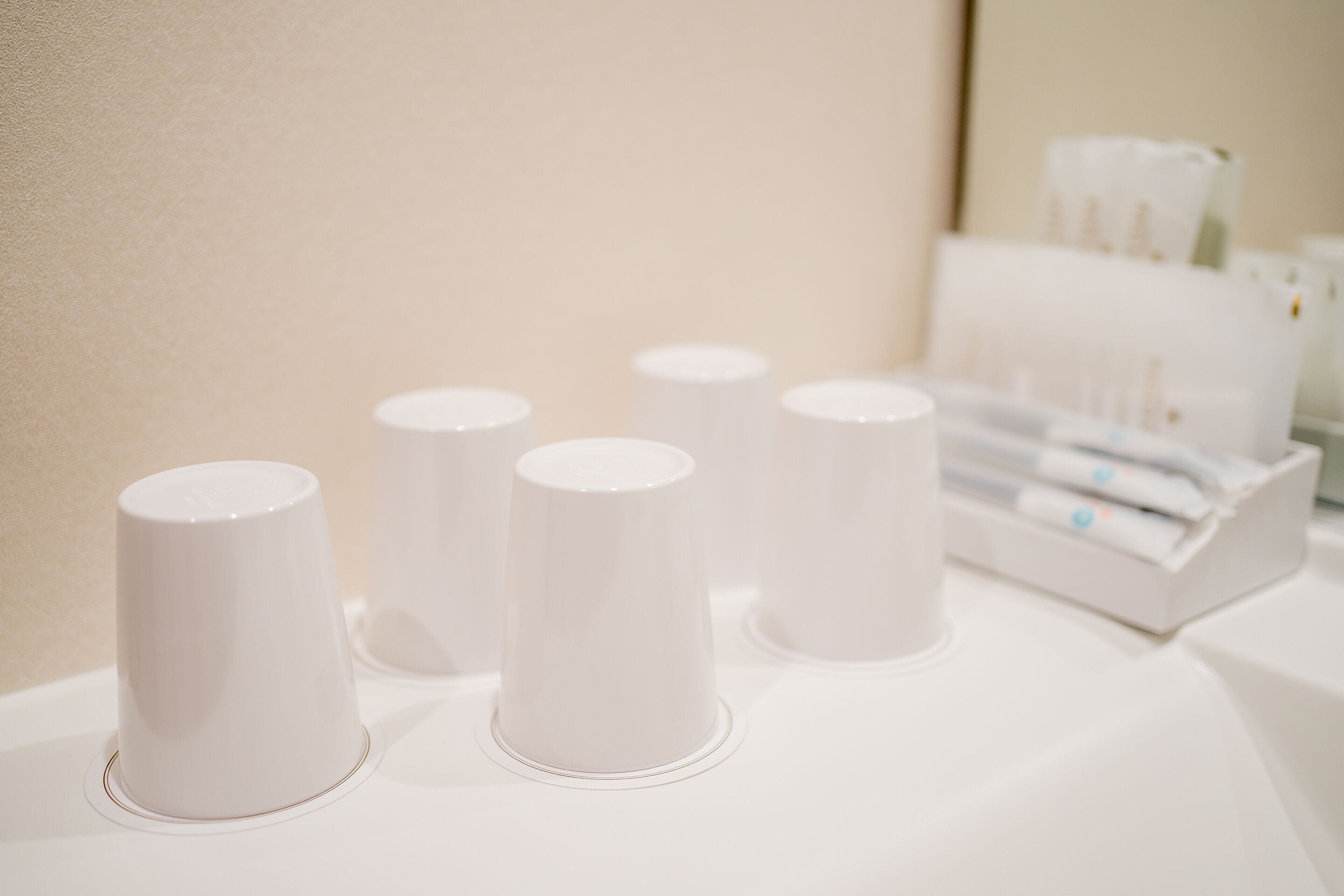 A row of white cylindrical containers on a white surface, likely for holding toiletries or amenities.