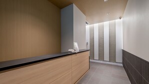 A modern bathroom with a wooden vanity, a towel rack, and a shower area with vertical blinds. - RESI STAY Nishijin  (Kyoto)