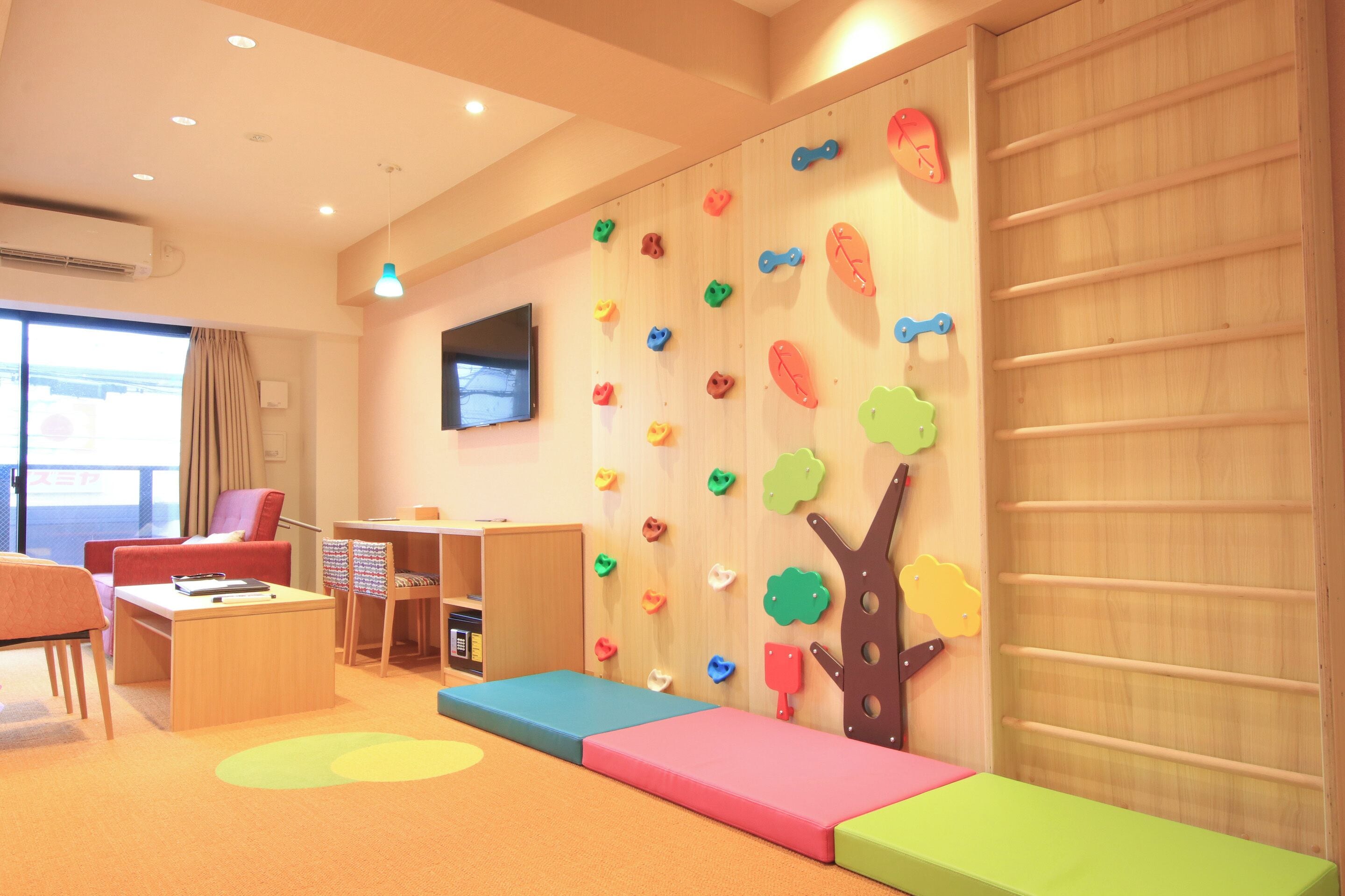 Habitación para niños con pared de escalar, zona de estar y televisor.