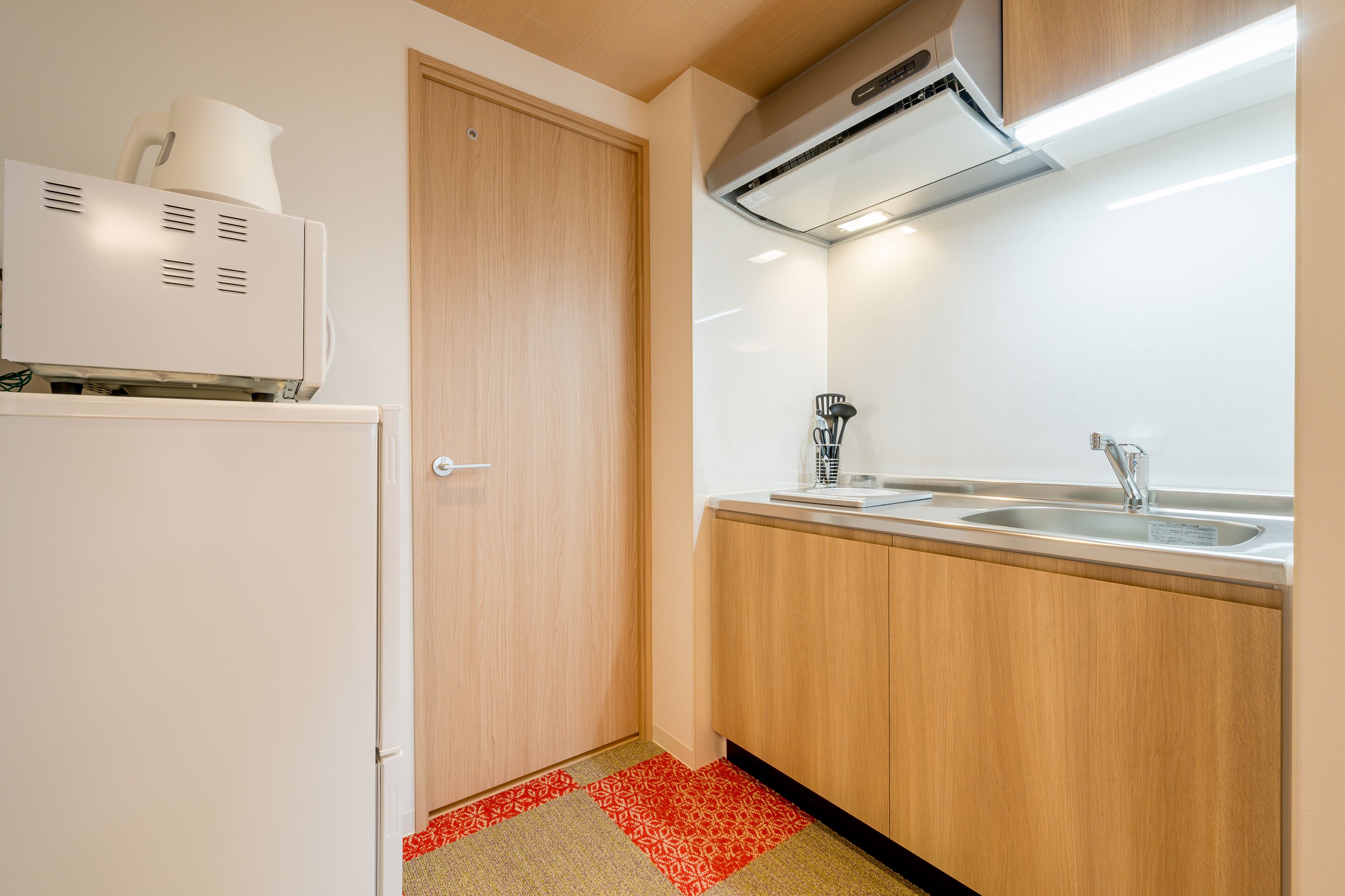 A compact kitchen with a refrigerator, a coffee maker, and a sink.