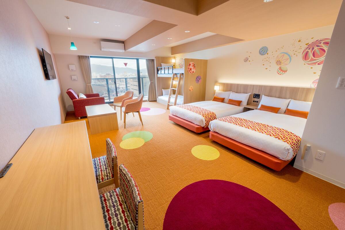 Ett hotellrum med två sängar, ett skrivbord, en stol och en balkong med utsikt.