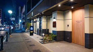 A hotel entrance with a modern design, featuring a wooden door labeled "RESI STAY" and a sign for "Nishijin." - RESI STAY Nishijin  (Kyoto)