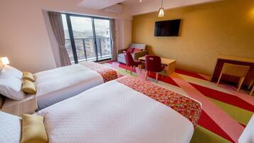 A hotel room with two beds, a desk, a chair, and a TV on the wall.