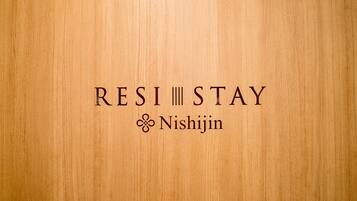 Un arrière-plan texturé en bois avec le texte « RESI STAY » et le logo « Nishijin ».