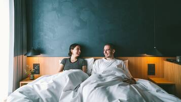 Un dormitorio con cama, mesitas de noche, lámpara y una lámpara de pared.