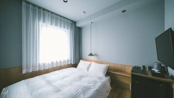 Una habitación de hotel con cama, escritorio y ordenador, además de televisión.