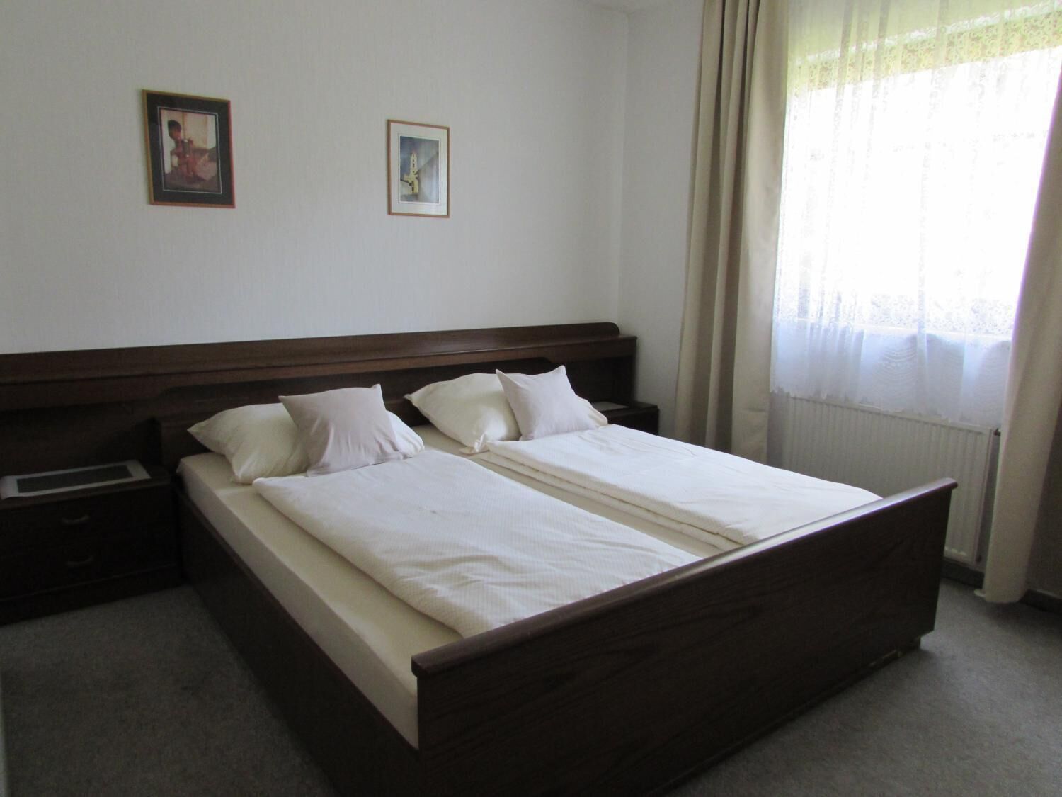 A standard hotel room with a double bed, two bedside tables, and a window with curtains.