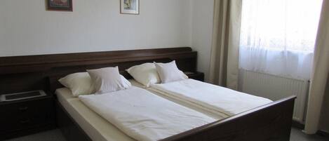 A standard hotel room with a double bed, two bedside tables, and a window with curtains.