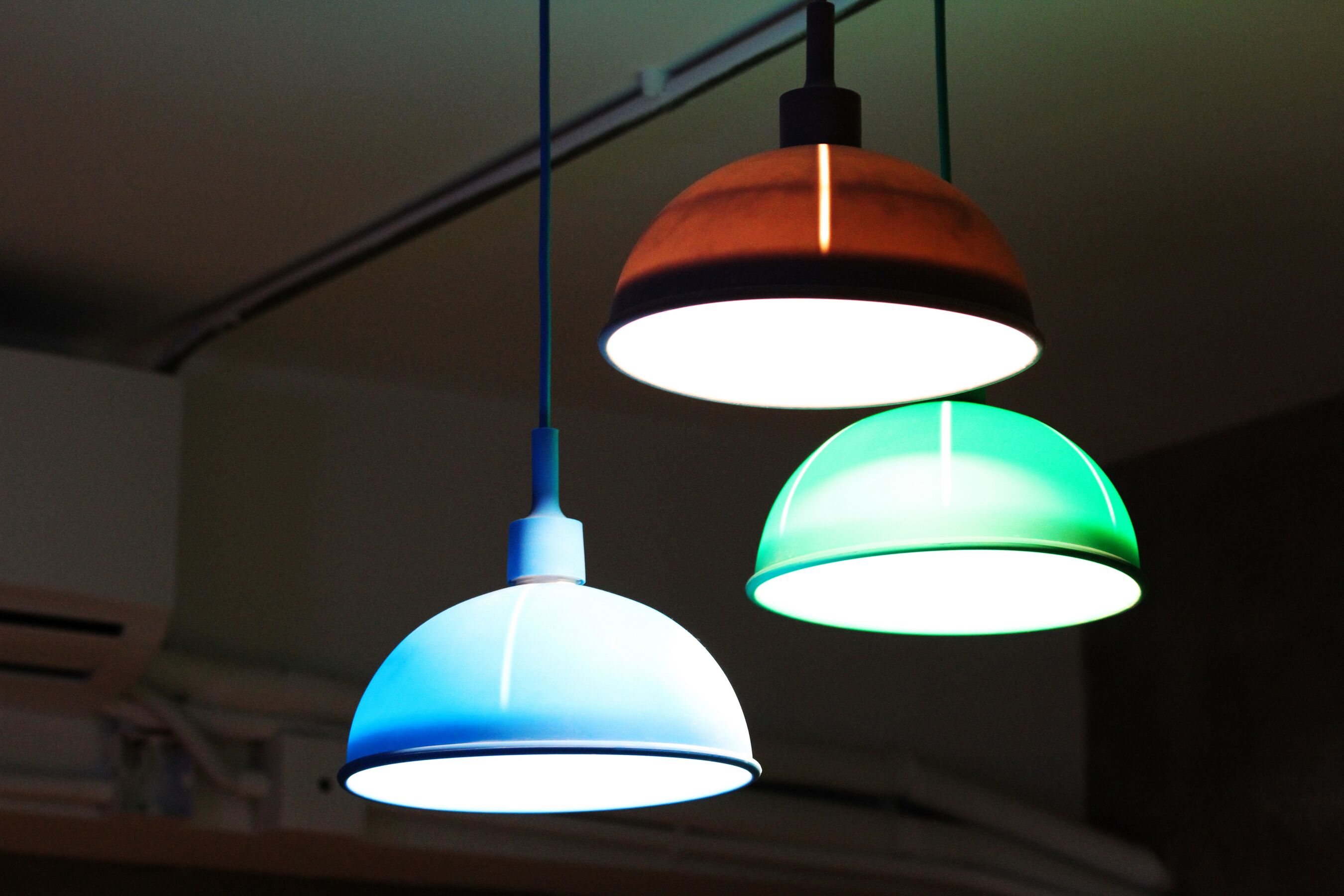 Trois suspensions de différentes couleurs sont suspendues au plafond.