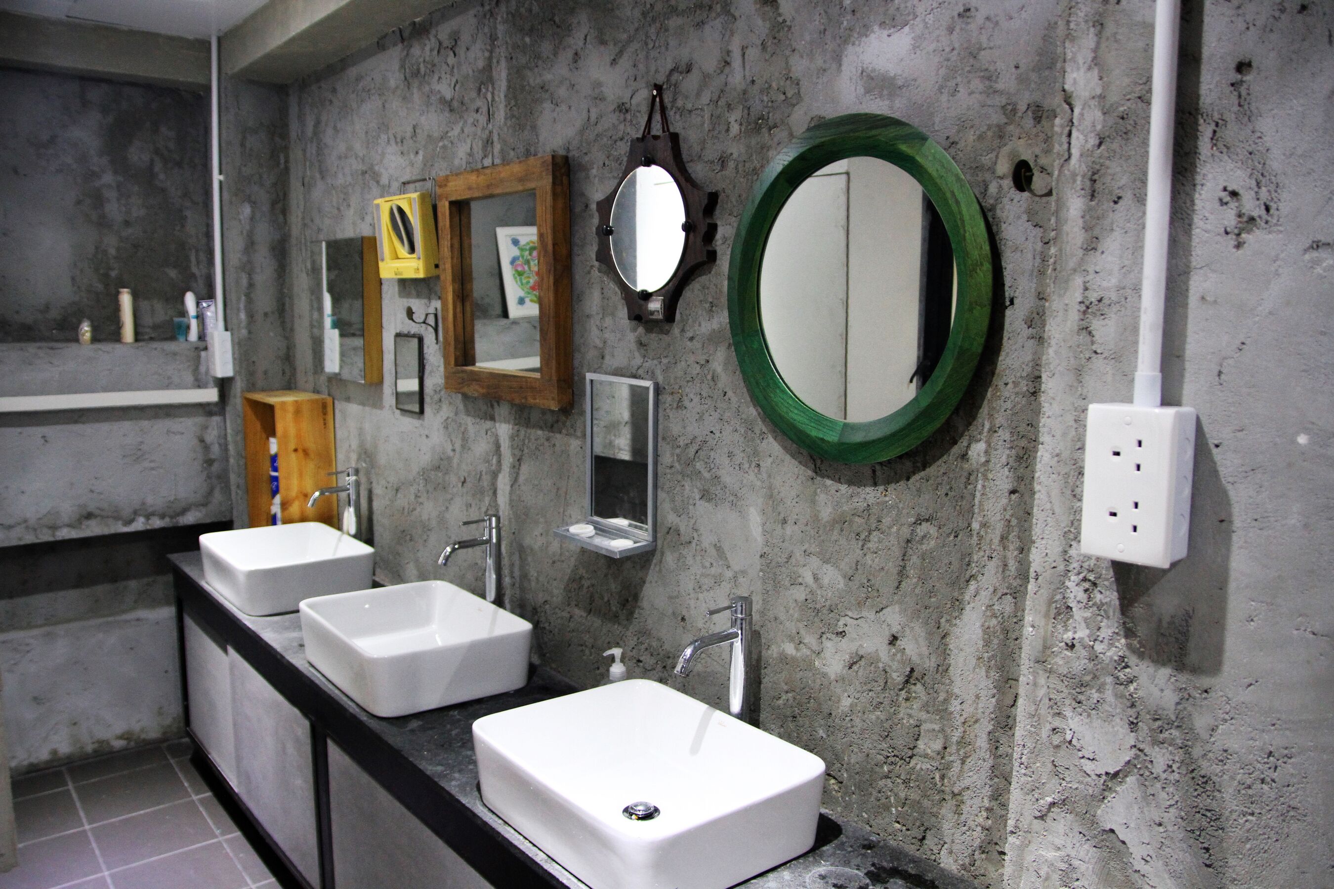 A bathroom with two sinks, a mirror, and a green-framed mirror.