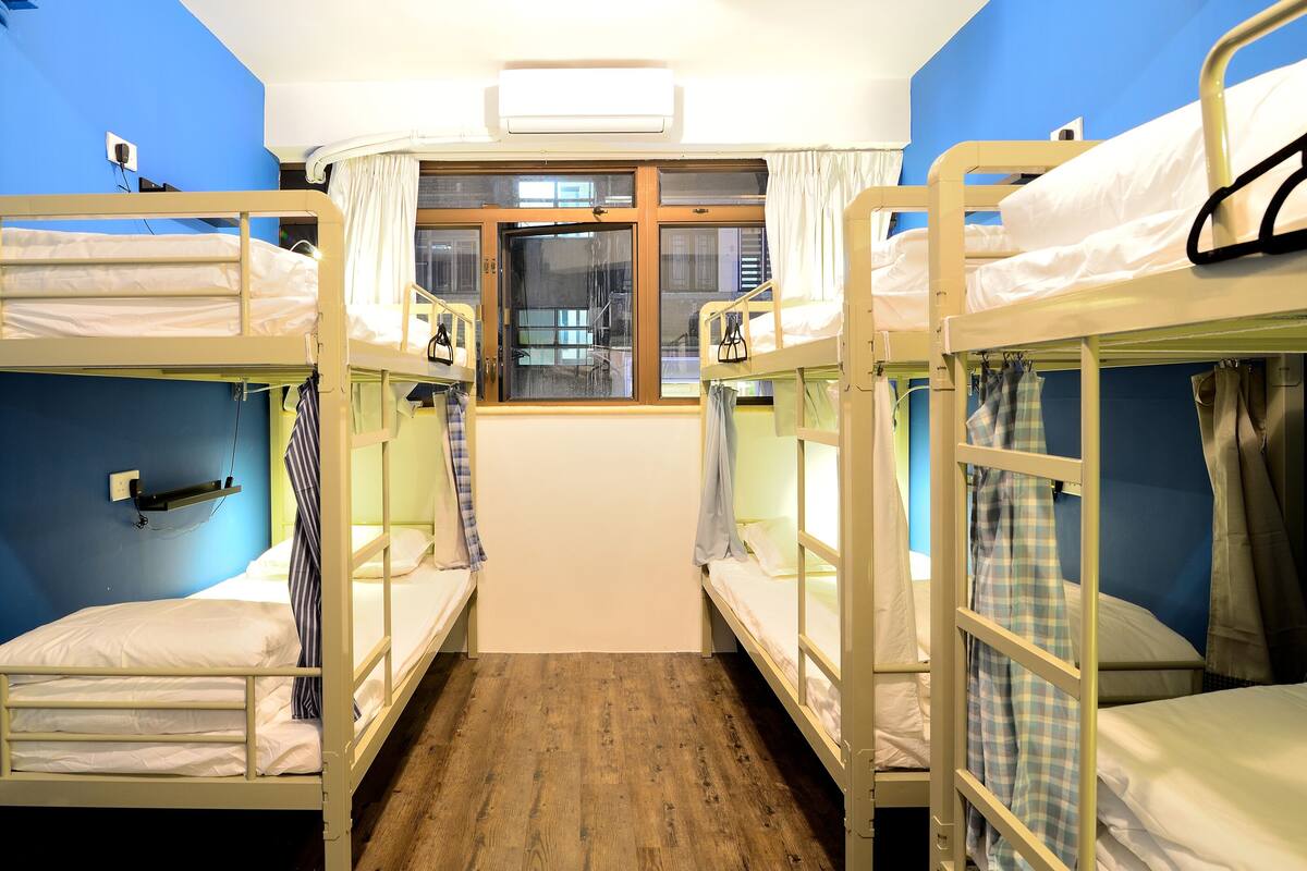 A room with bunk beds, a window with curtains, and an air conditioning unit.