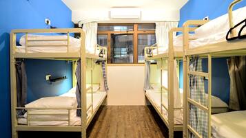 A room with bunk beds, a window with curtains, and an air conditioning unit.
