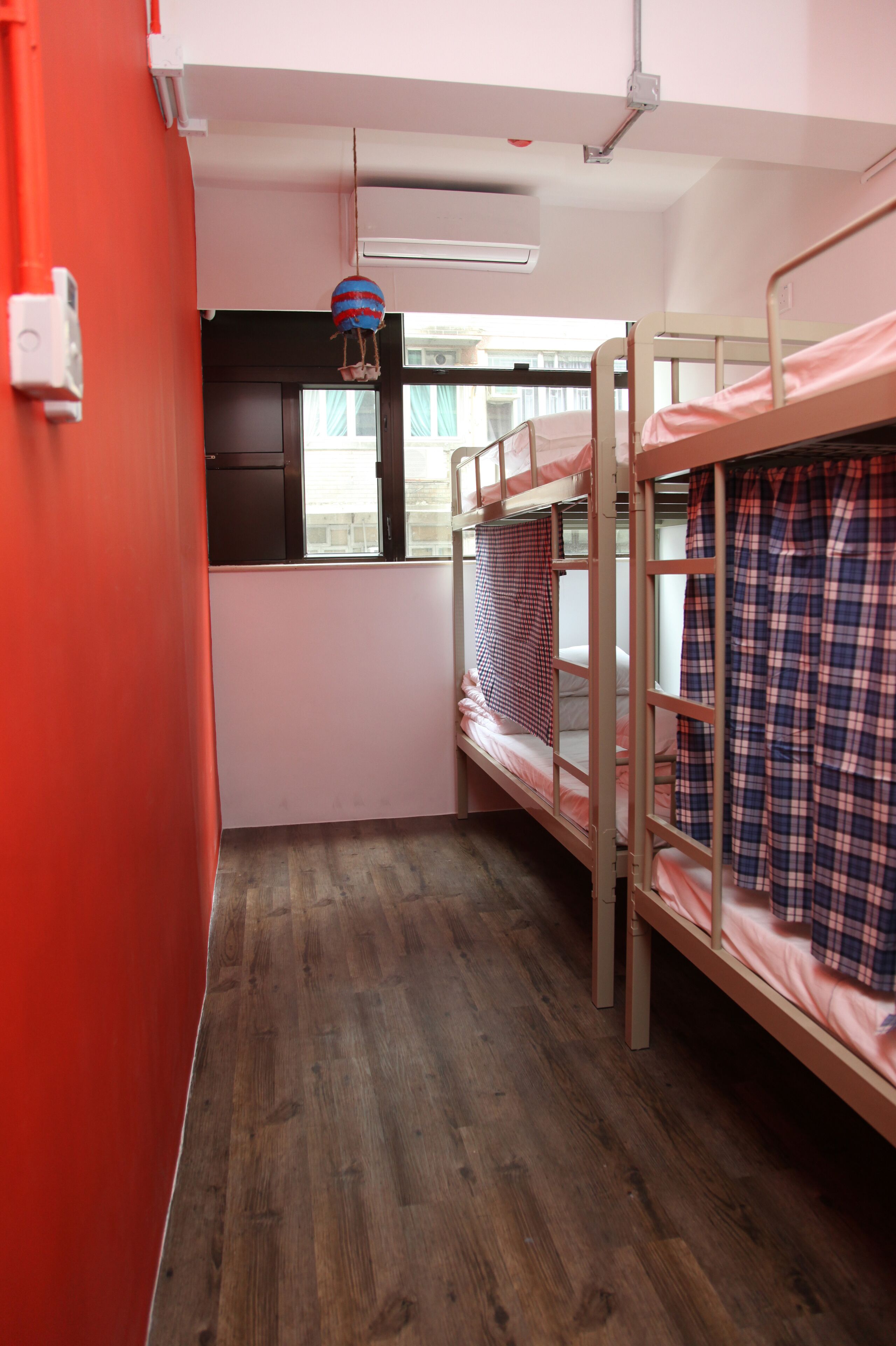 A bunk room with two bunk beds, a window, and a red wall.