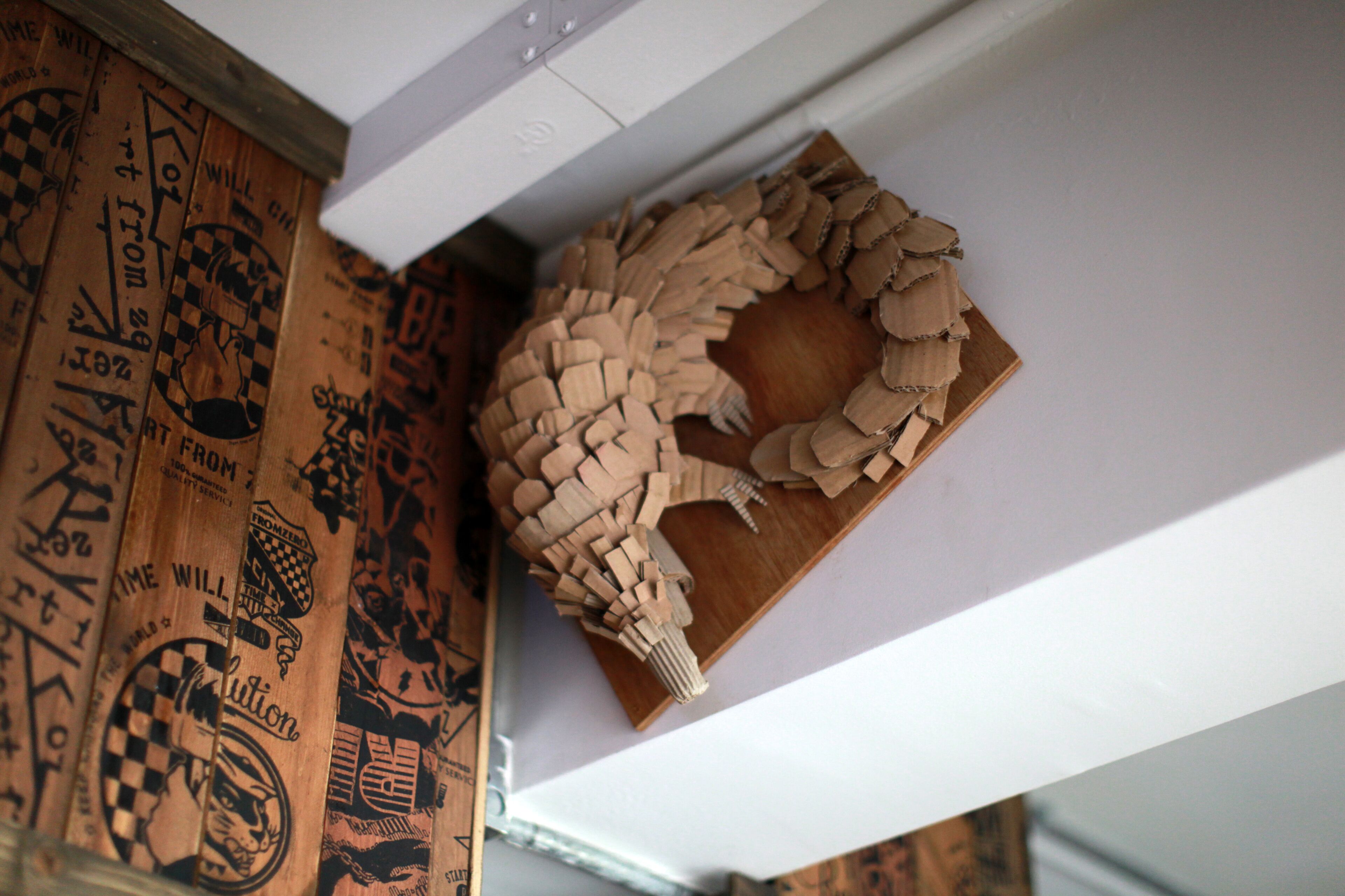 A wooden wall with a circular pattern and a wooden shelf with a woven design.