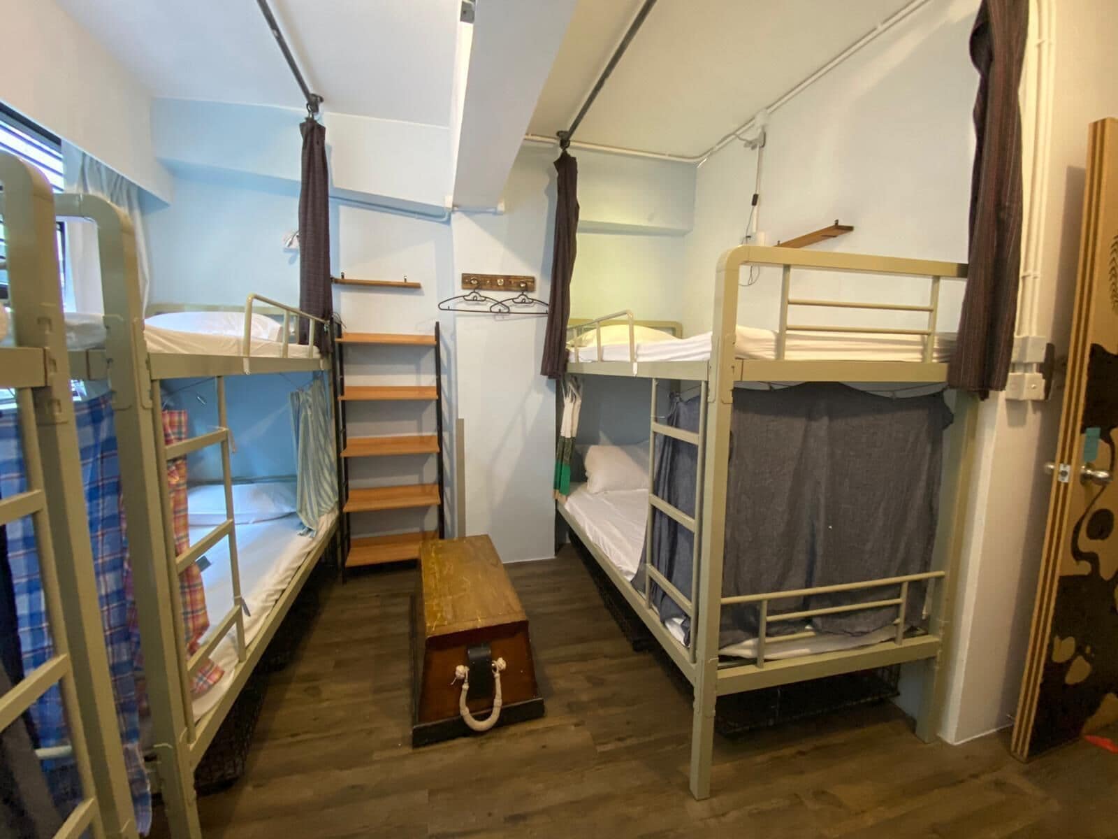 A dormitory room with bunk beds, a wooden bench, and a small table.