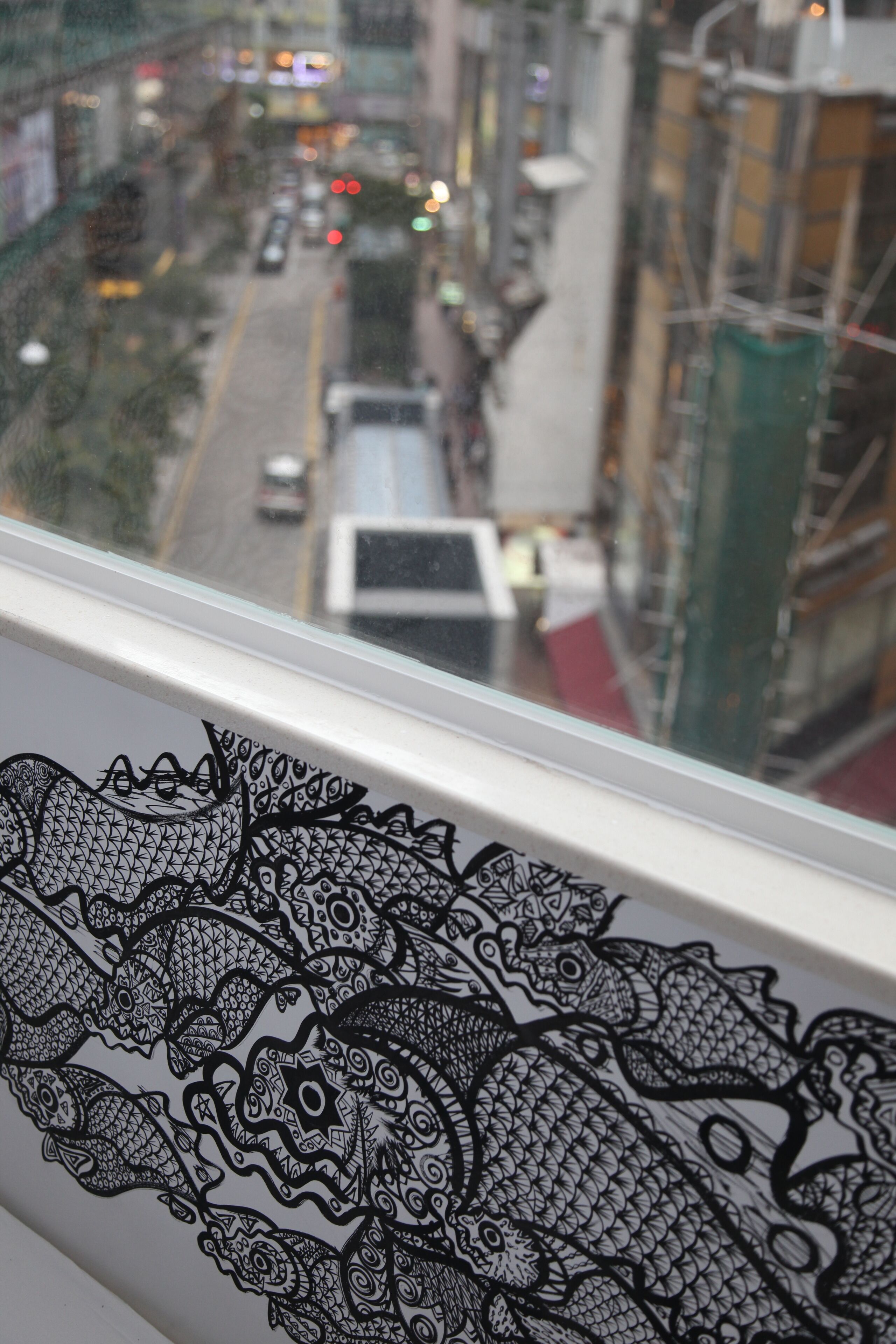 A window view of a city street with buildings and vehicles.
