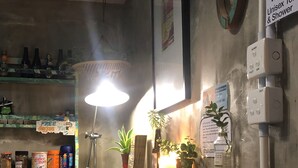 A bar area with a wooden counter, white chairs, a hanging light, and a sign indicating unisex toilet and shower facilities. - Hop Inn - Hostel (Kowloon)