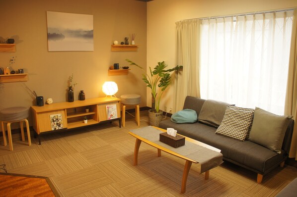 A living room with a sofa, a coffee table, a lamp, a plant, and a painting on the wall.