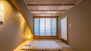 Et traditionelt japansk rum med tatamigulv, to tatami-måtter, et lavt træloft og en skydedør, der fører til et andet rum.