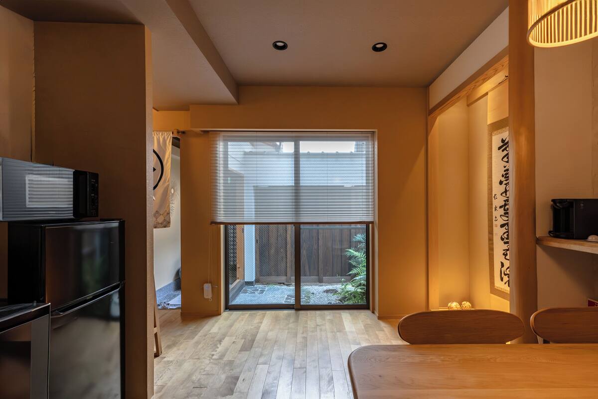Una cocina moderna con refrigerador, una mesa de comedor y una puerta corrediza de vidrio que da a un patio trasero.