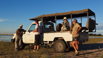 Veículo safari branco com teto, estacionado à beira da água.
