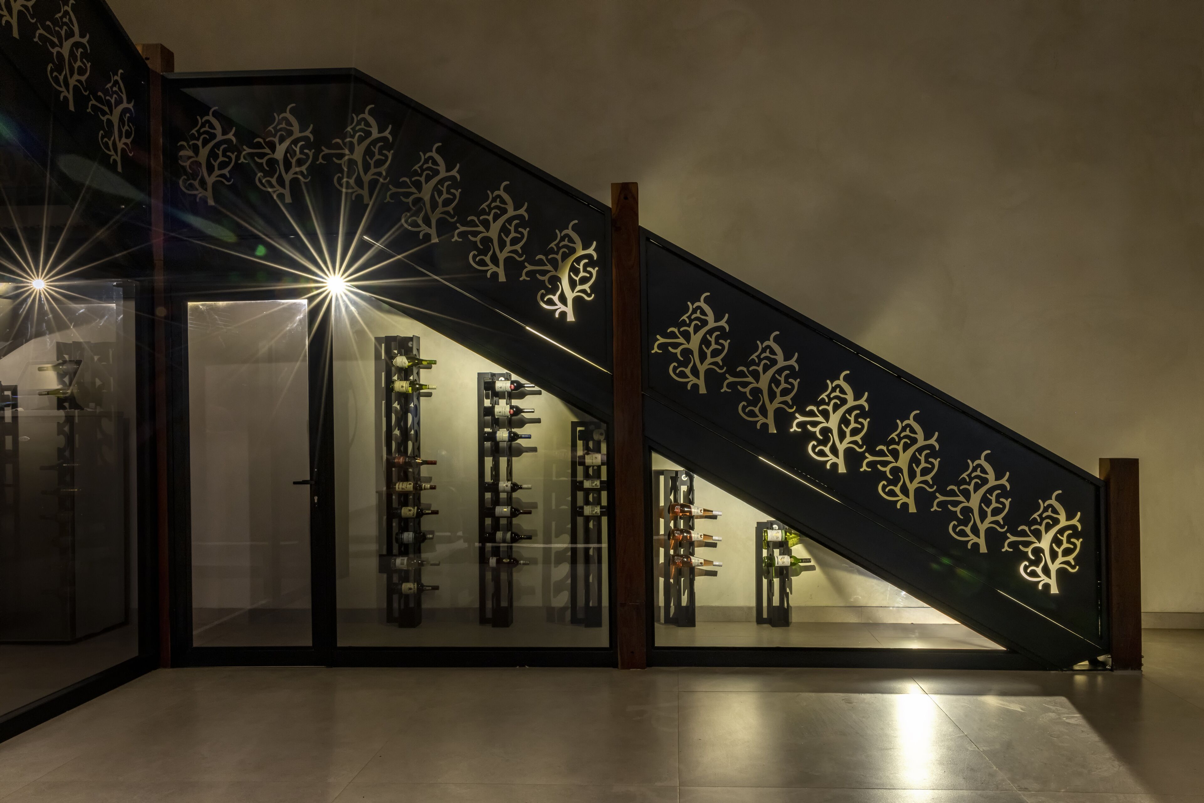 Una escalera con diseños decorativos y una estantería para vinos en la parte inferior.