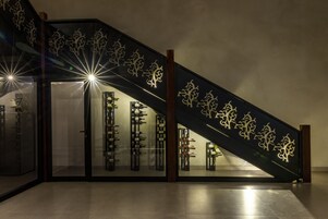 Una escalera con diseños decorativos y una estantería para vinos en la parte inferior.