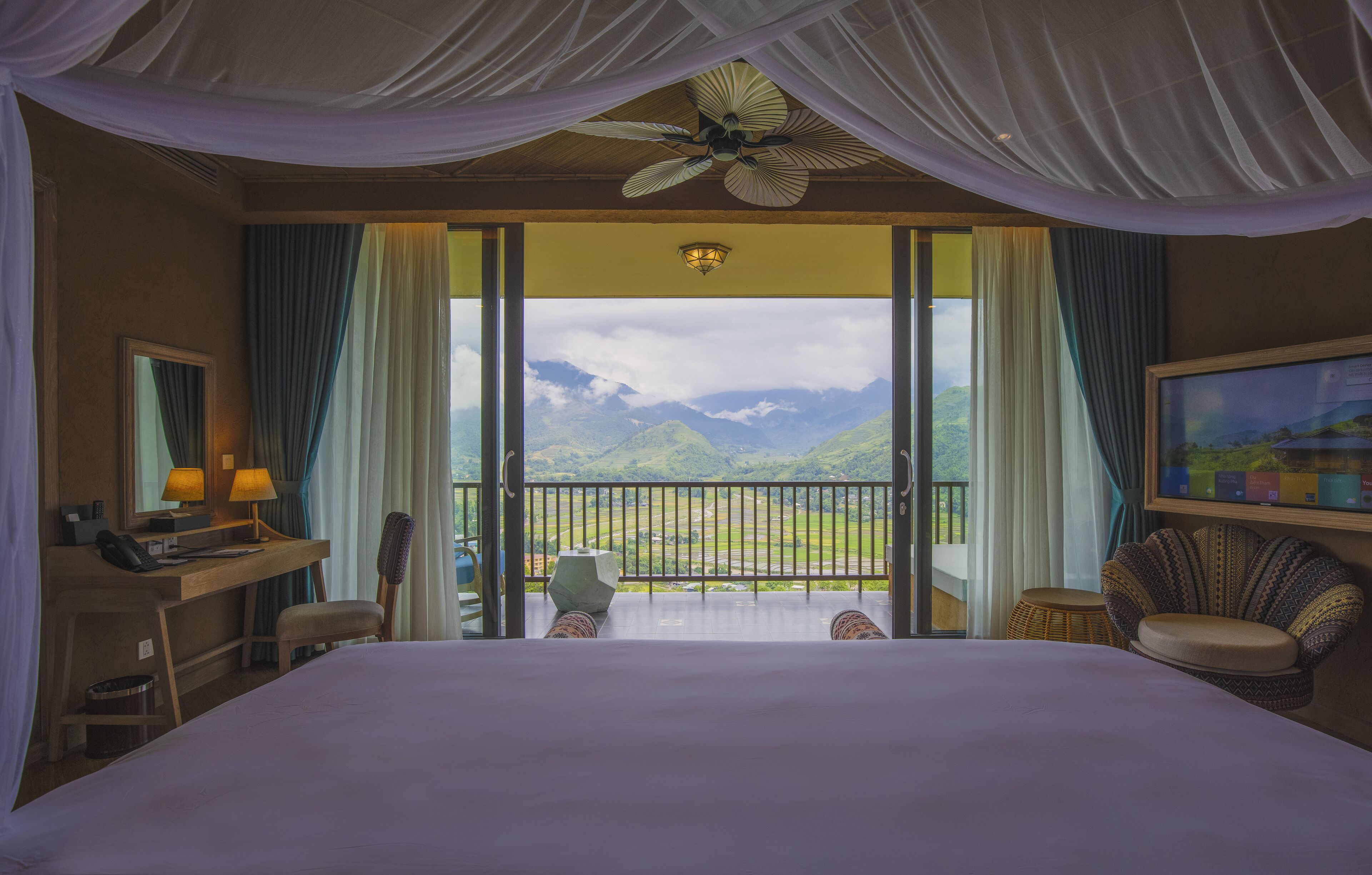 Une chambre d’hôtel équipée d’un lit, d’un bureau, d’une chaise et d’un balcon avec vue sur la montagne.