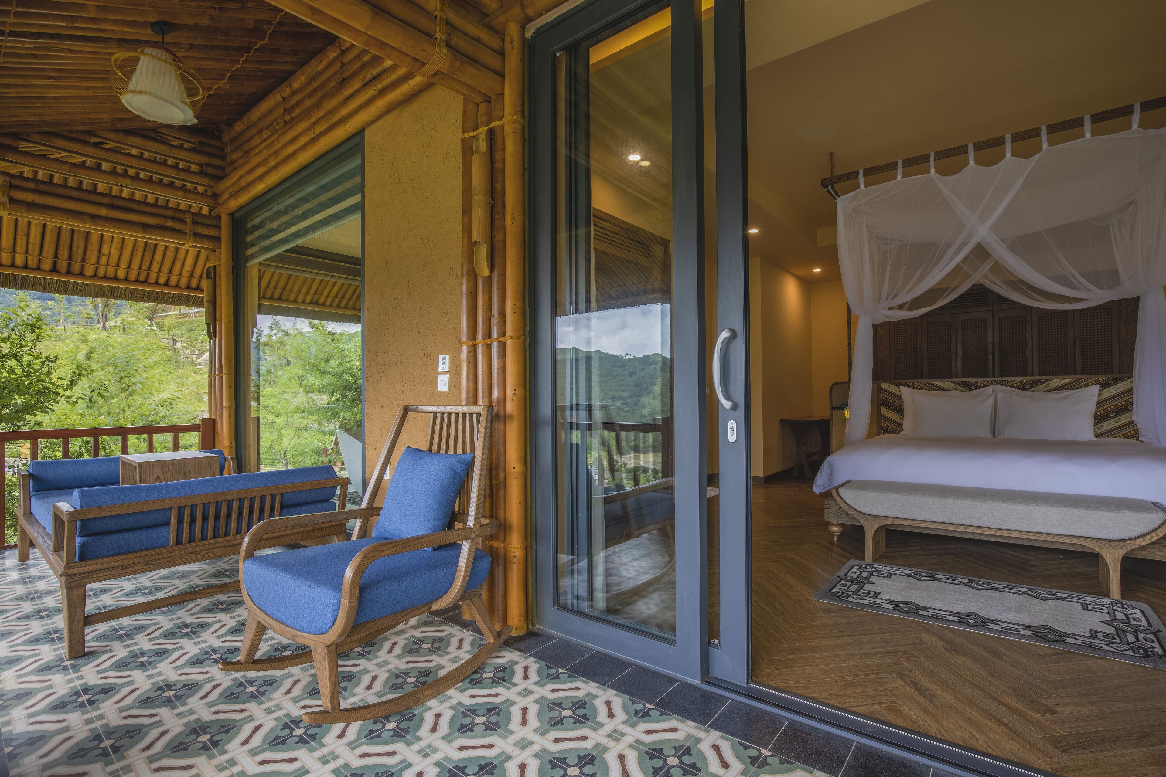 A room with a bed, a glass door leading outside, and a seating area with chairs and a sofa.