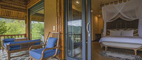 A room with a bed, a glass door leading outside, and a seating area with chairs and a sofa.