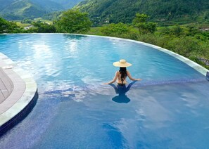 Una mujer en una piscina con vista a un paisaje montañoso.