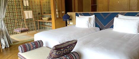 Ein Hotelzimmer mit einem großen Bett, zwei Kissen, einem Holz-Kopfschild, einem Hängesessel und einer Wand mit Muster.