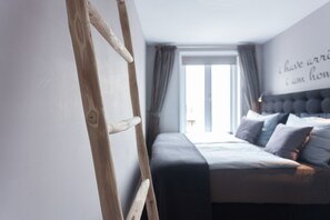 A bedroom with a bed, a wooden ladder, a window with curtains, and a wall with a partial text. - Bed and Breakfast The Rose (Haarlem)