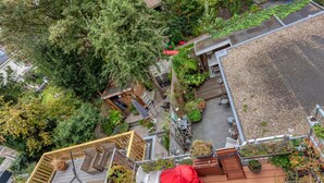 An aerial view of a rooftop garden with wooden decking, outdoor furniture, and potted plants. - Bed and Breakfast The Rose (Haarlem)