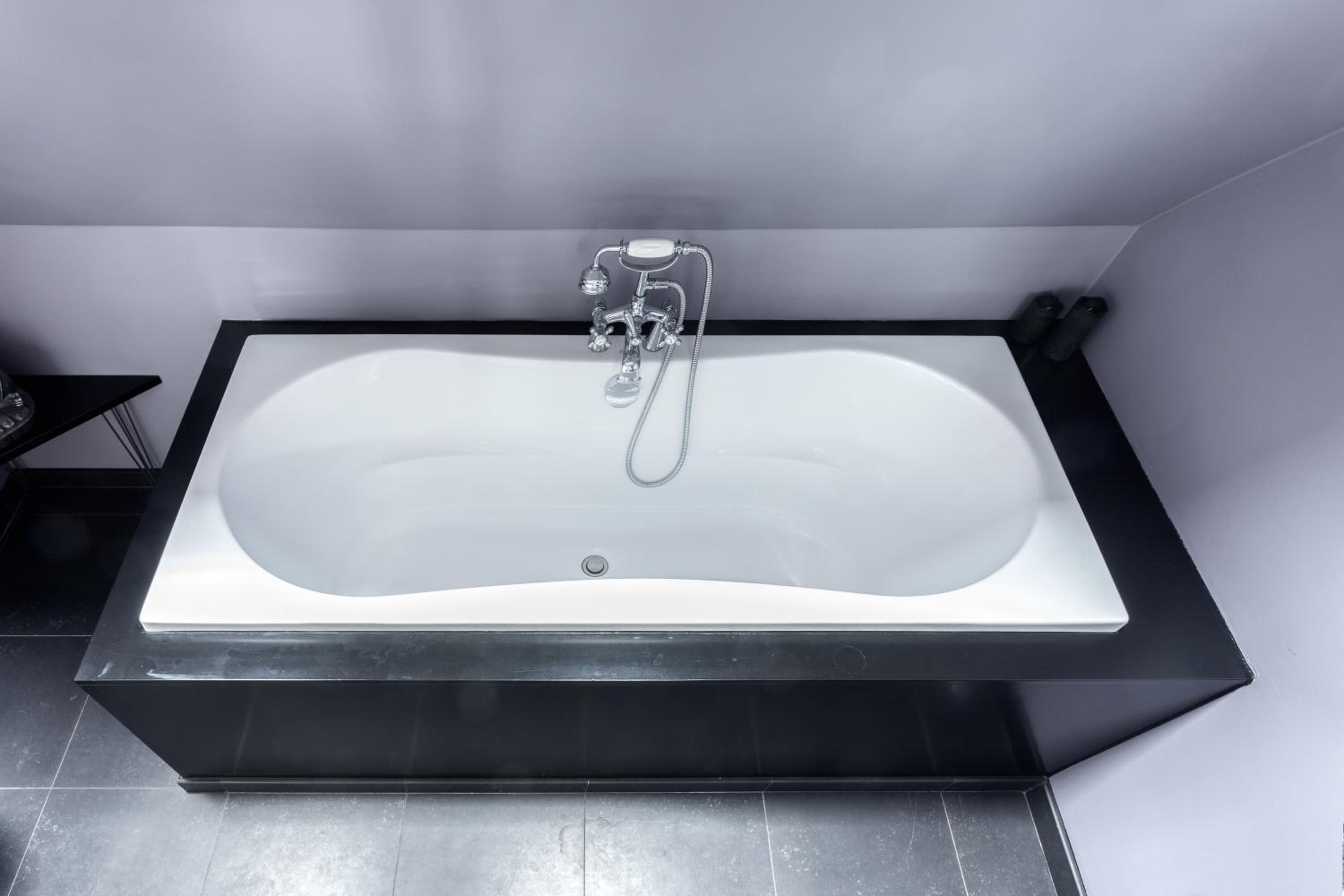 Ein modernes Badezimmer mit einer freistehenden Badewanne, einem schwarzen Waschbecken und einem Spiegel.