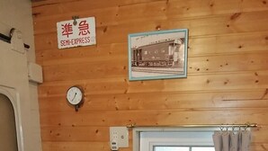 A compact kitchen with a microwave, toaster, and small refrigerator. A clock and a framed picture are on the wall. - Country House Morning Salad (Fujikawaguchiko)
