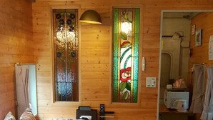 A cozy room with a large bed, wooden walls, a stained glass window, and a small kitchenette. - Country House Morning Salad (Fujikawaguchiko)