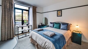 A bedroom with a bed, bedside table, lamp, and a desk with a chair. - Garden facing studio with Juliet balcony. Walk to seafront, shops & restaurants. (Portsmouth)
