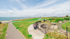 A coastal walkway with a bench, a gazebo, and a view of the sea. - Garden facing studio with Juliet balcony. Walk to seafront, shops & restaurants. (Portsmouth)