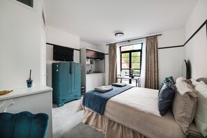 A bedroom with a bed, a desk, a wardrobe, and a kitchenette. - Garden facing studio with Juliet balcony. Walk to seafront, shops & restaurants. (Portsmouth)
