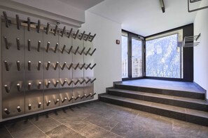 A modern interior with a wall-mounted coat rack and a staircase leading to a balcony with a city view.