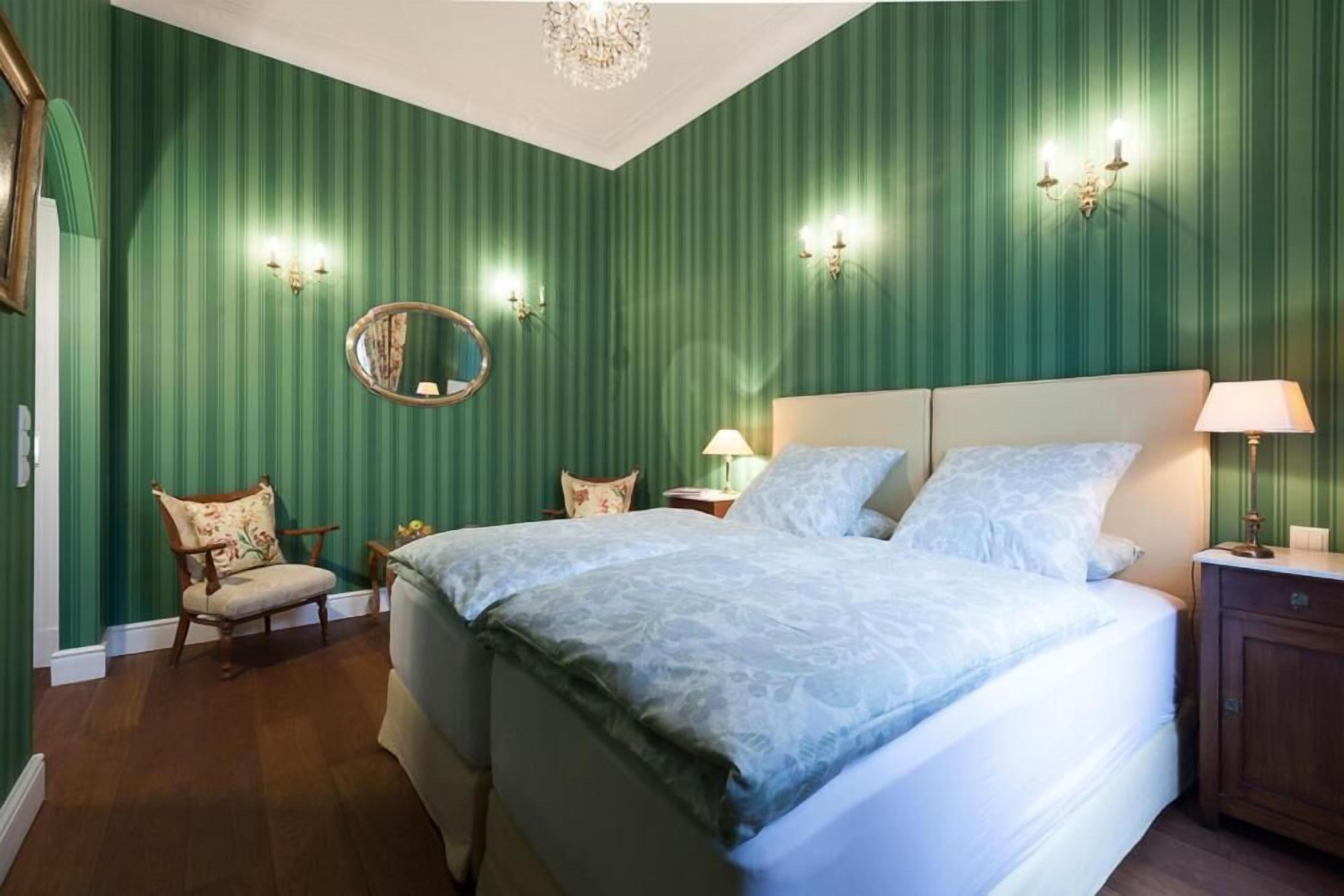 A bedroom with a large bed, a chair, a nightstand, and a dresser.