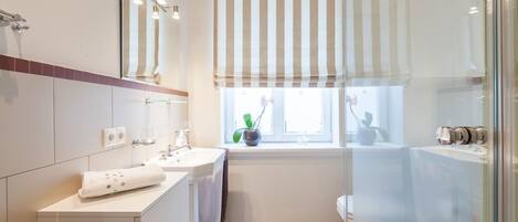 Un bagno moderno con due lavandini, uno specchio grande, una finestra vista esterna e una zona doccia.