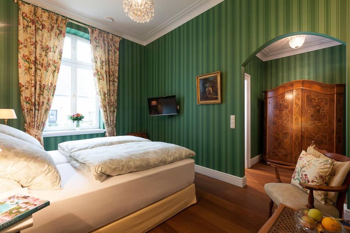 A bedroom with a bed, a television, a wooden wardrobe, and a chair.