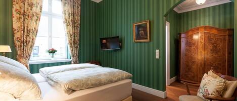 Un dormitorio con cama, televisor, armario de madera y una silla.